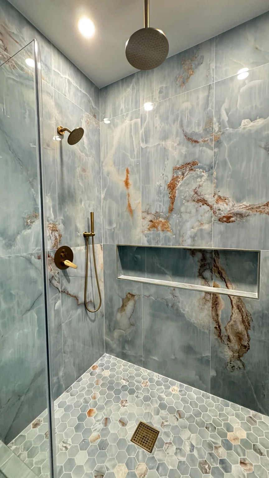 Detail of shower with richly veined tile and brass hardware