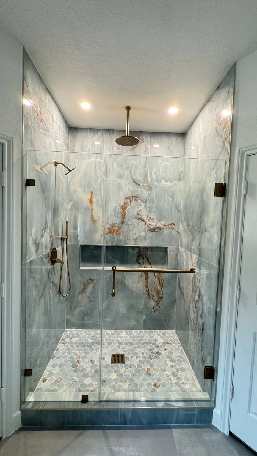 Renovated shower with blue stone-look tile and brass fixtures