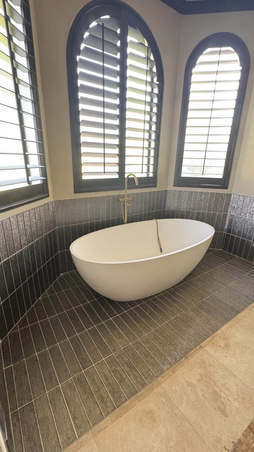 Freestanding bathtub beside arched windows